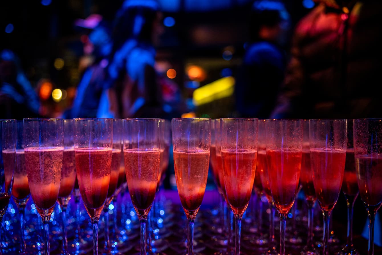A table full of pink cocktails in champagne flutes.