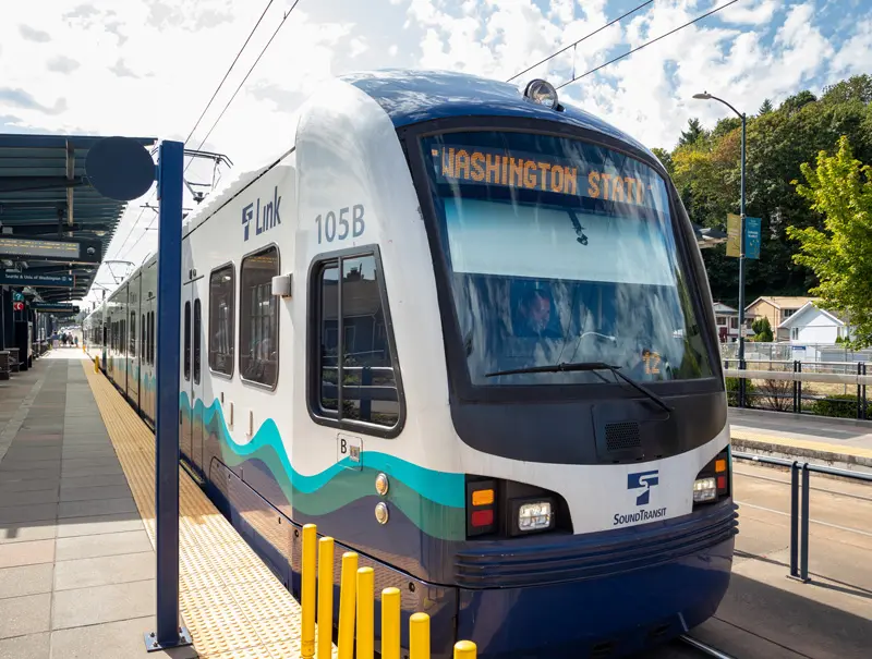 A Sound Transit Link light rail train stopped at a station on a sunny day.